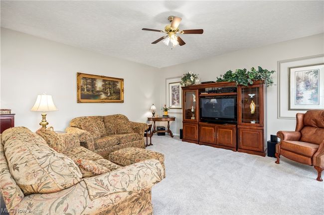 Living room with ceiling fan, light carpet, and a textured ceiling | Image 18