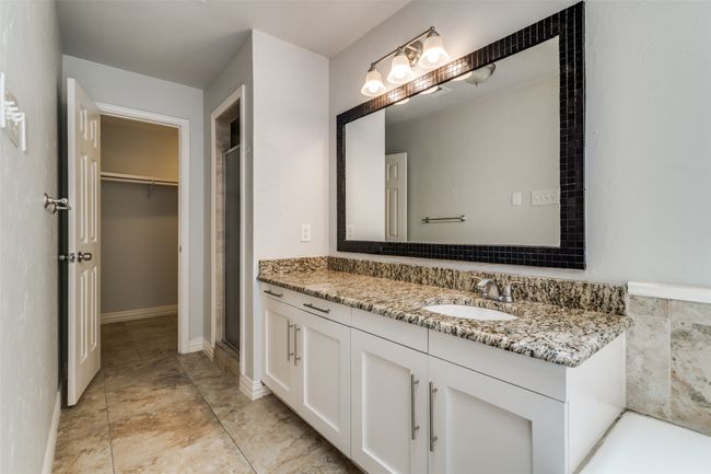 Primary bathroom showing one of the two vanities and one of the two walk in closets and the walk in shower. | Image 18