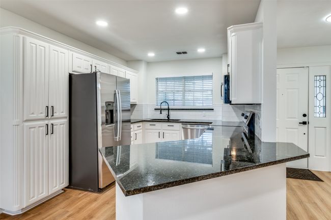 Kitchen with a peninsula, appliances with stainless steel finishes, a sink, light wood finished floors, and decorative backsplash | Image 10