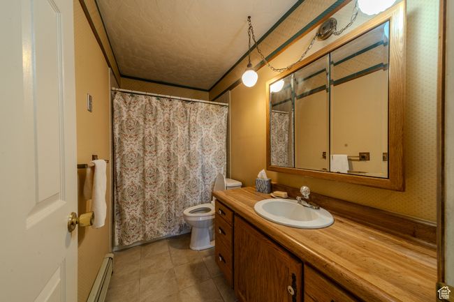 Bathroom with tile patterned flooring, toilet, vanity, and a textured ceiling | Image 28