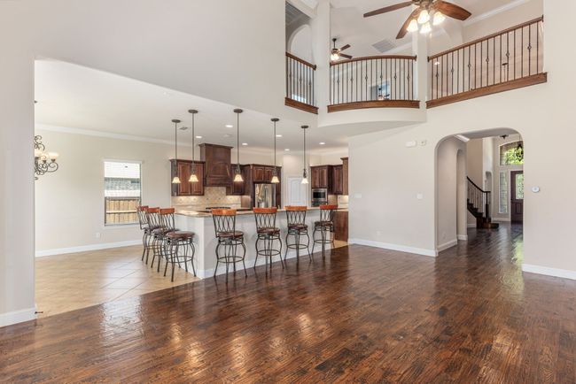 Living room featuring wood finished floors, arched walkways, crown molding, baseboards, and ceiling fan | Image 18