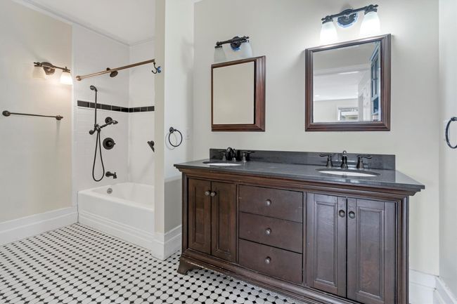 Bathroom featuring double vanity, tub / shower combination, baseboards, and tile patterned floors | Image 24