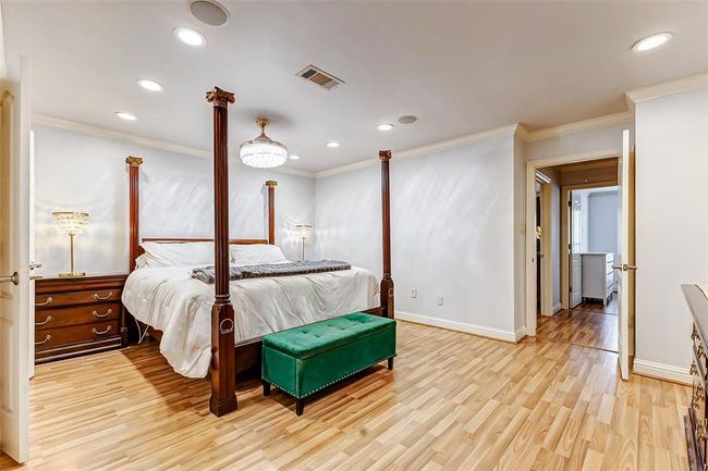This expansive retreat offers enough space for both a sleeping area and a cozy sitting nook. A four-poster bed takes center stage, enhanced by a combination of recessed lighting and a semi-flush mounted fixture. Soft neutral tones create a calming ambiance, while the en suite bath adds to the room’s luxury. | Image 24