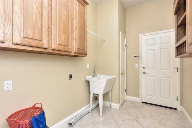 Laundry room with electric washer and dryer hookups, sink, drying rod and cabinets. | Image 16