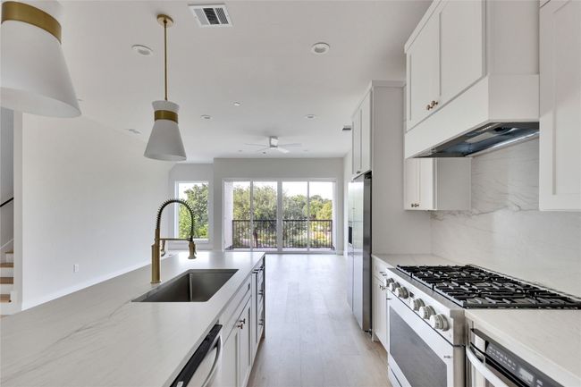 Kitchen with stainless steel appliances, a sink, backsplash, a ceiling fan, and white cabinets | Image 25