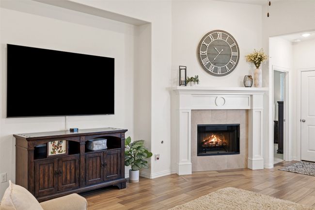 Cozy up by the fireplace, featuring a clean white surround and a timeless wooden mantle that complements any decor. | Image 17