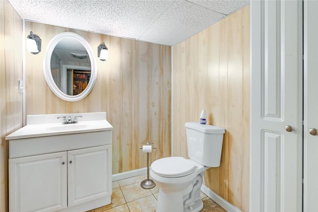 Half bathroom featuring toilet, vanity, tile patterned floors, and wooden walls | Image 29