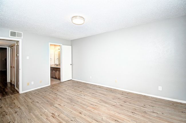 Unfurnished bedroom featuring ensuite bathroom, light wood-type flooring, and a textured ceiling | Image 18