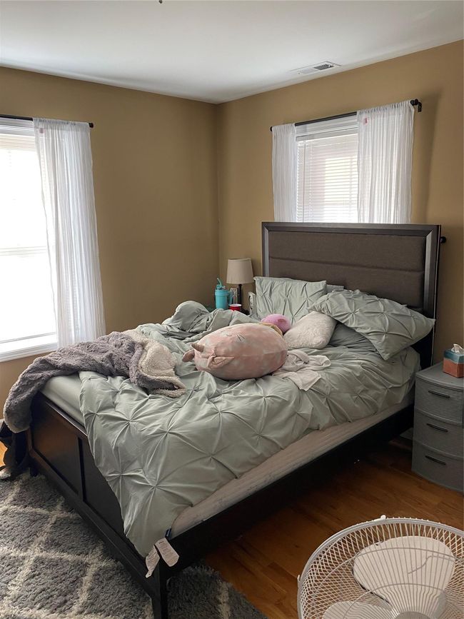 Bedroom with visible vents, wood finished floors, and multiple windows | Image 9
