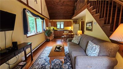 Living room featuring high vaulted ceiling, hardwood / wood-style flooring, a baseboard radiator, and sink | Image 2