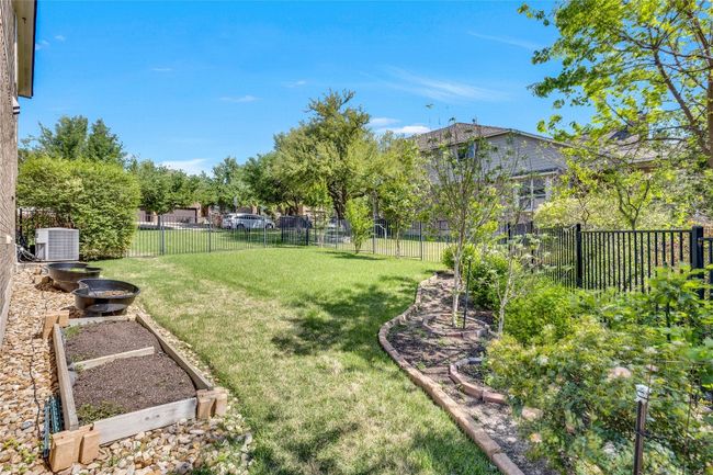View of side yard featuring a garden bed and a iron fenced backyard | Image 32