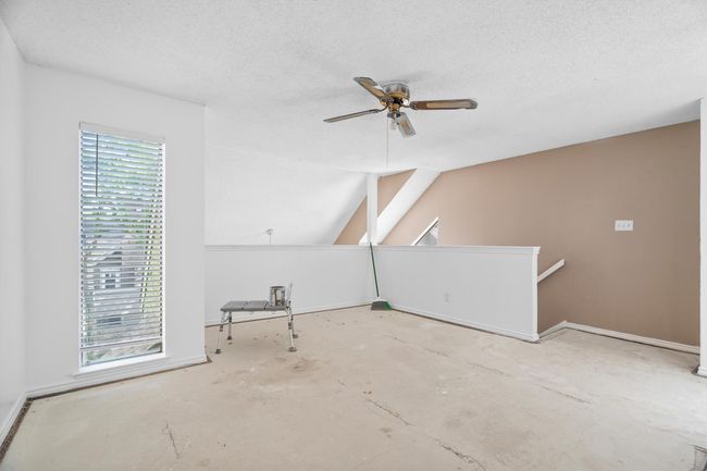 Bonus room featuring ceiling fan, concrete flooring, a textured ceiling, and lofted ceiling | Image 12