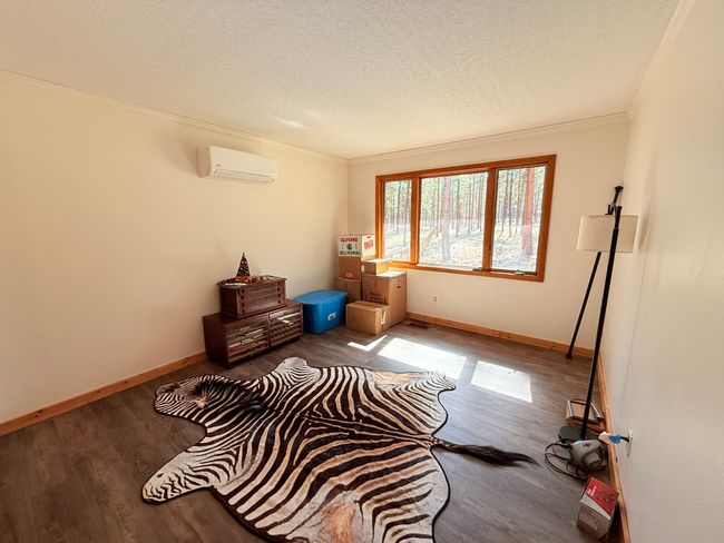Bedroom with a textured ceiling, ornamental molding, wood finished floors, and a wall unit AC | Image 46