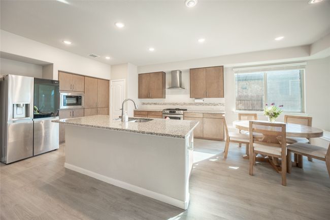 Kitchen with a kitchen island with sink, sink, tasteful backsplash, appliances with stainless steel finishes, and wall chimney exhaust hood | Image 6