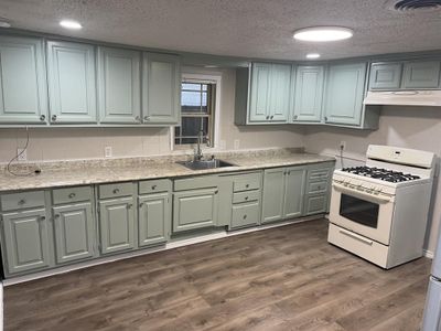 Kitchen featuring dark hardwood / wood-style floors, white gas range oven, ventilation hood, sink, and a textured ceiling | Image 3