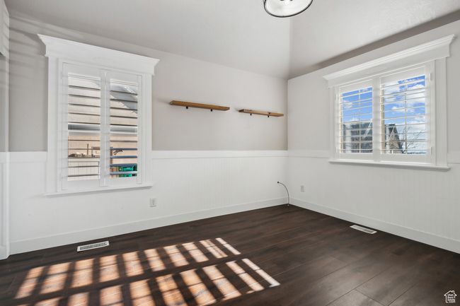 Unfurnished bedroom room featuring vaulted ceiling and dark hardwood / wood-style flooring. Plantation shutters. | Image 23