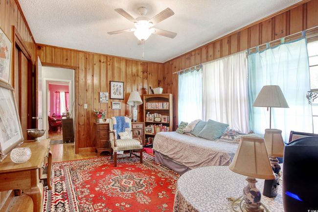 Bedroom featuring wood finished floors, wooden walls, a textured ceiling, ornamental molding, and ceiling fan | Image 19