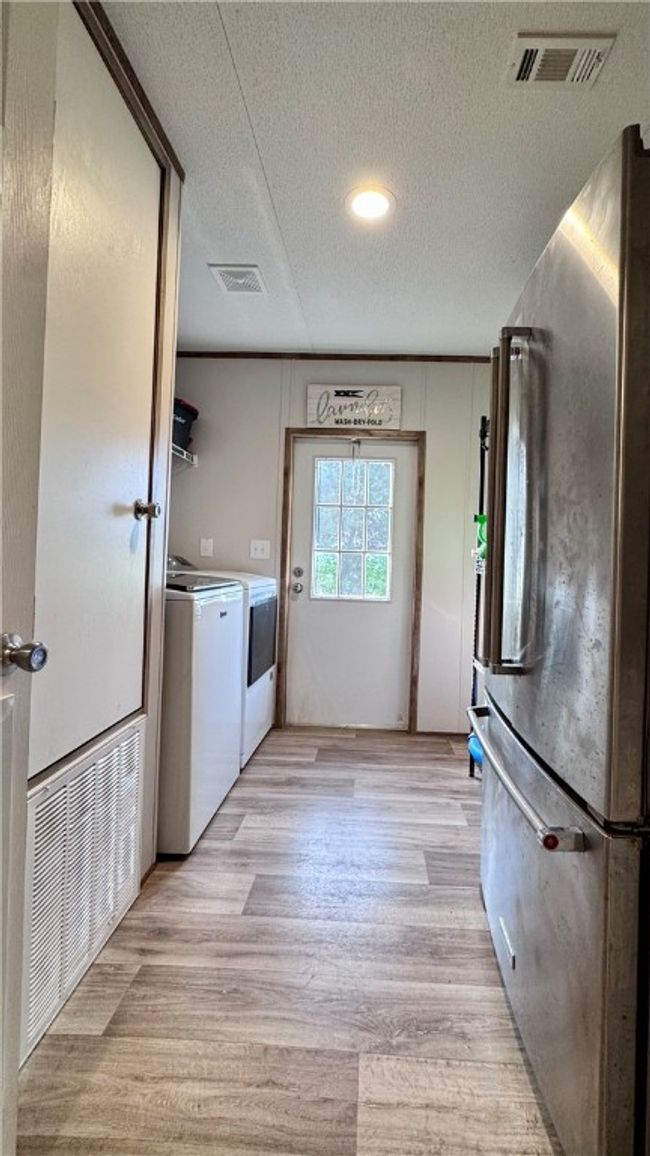 Laundry room with a textured ceiling, independent washer and dryer, and light wood-style floors | Image 17