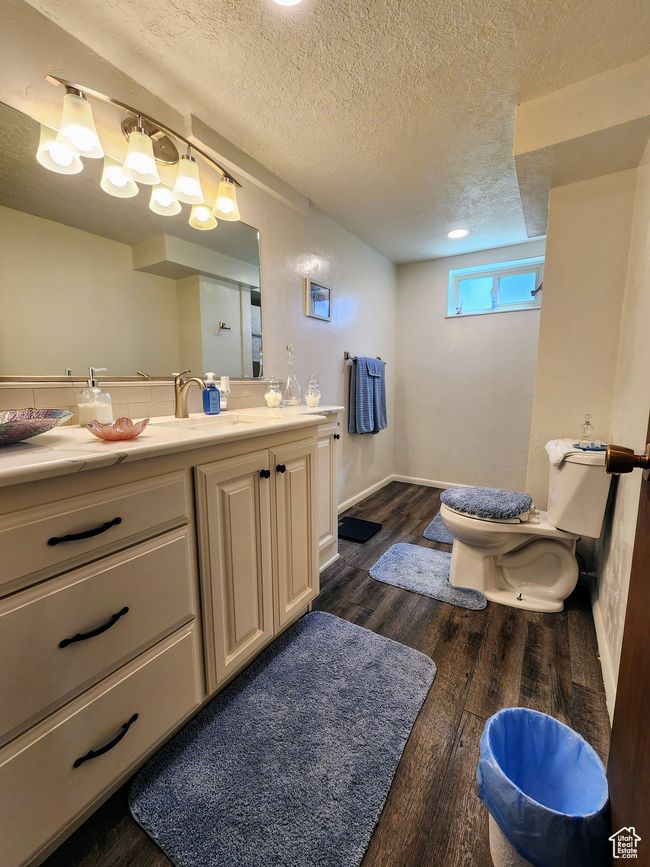 Bathroom with vanity, wood finished floors, toilet, baseboards, and a textured ceiling | Image 37