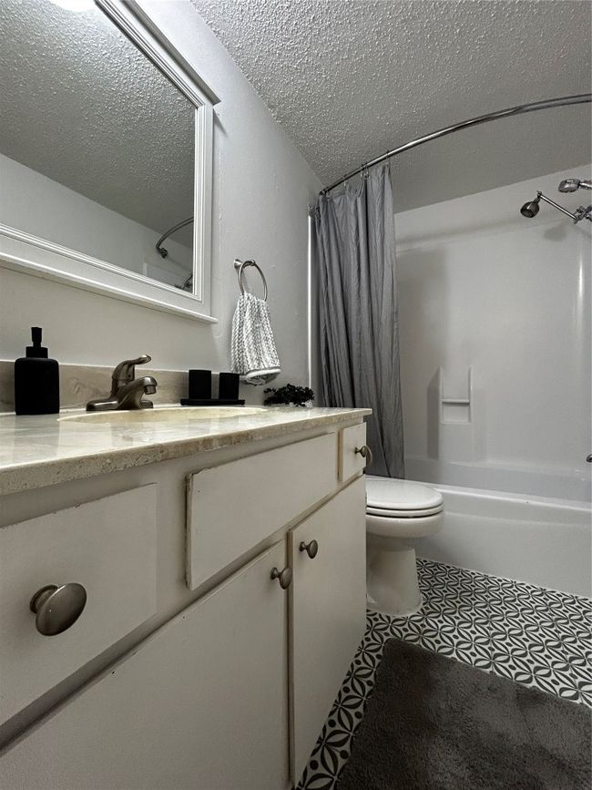 Bathroom featuring vanity, shower / bath combo, light tile patterned flooring, and a textured ceiling | Image 7