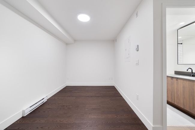 Empty room with a baseboard radiator, wood finished floors, and electric panel | Image 26