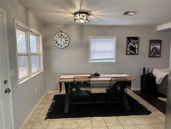 Dining room with light tile patterned flooring and a textured ceiling | Image 5