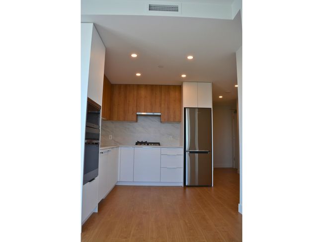 Kitchen featuring oven, modern cabinets, freestanding refrigerator, visible vents, and recessed lighting | Image 6