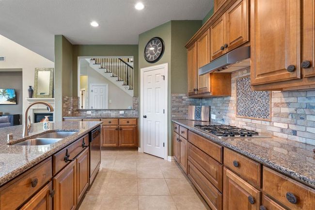 The wood tones with the stone backsplash accentuates the kitchen. | Image 16