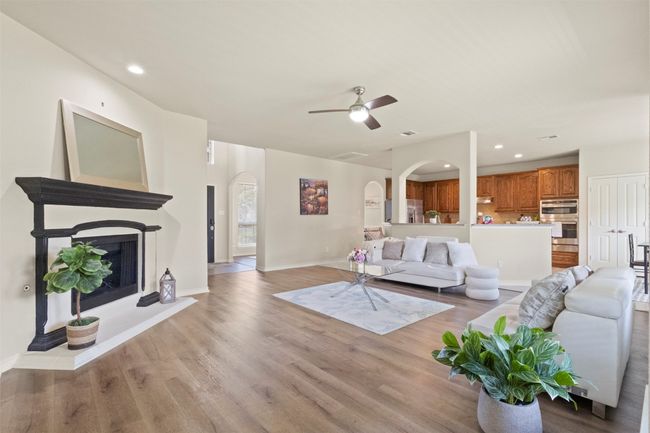 Living room featuring arched walkways, light wood-style flooring, a ceiling fan, baseboards, and recessed lighting | Image 7