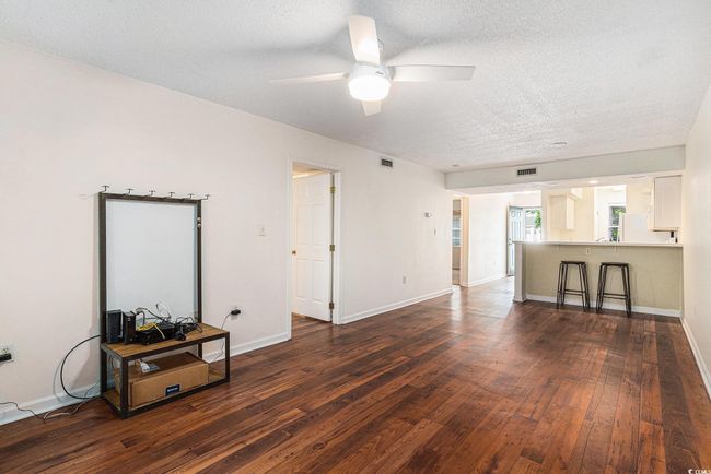 Living area featuring dark wood-style flooring, a ceiling fan, a textured ceiling, and baseboards | Image 25