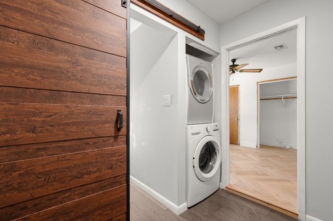 Washroom with a barn door, laundry area, stacked washer / dryer, a ceiling fan, and baseboards | Image 29
