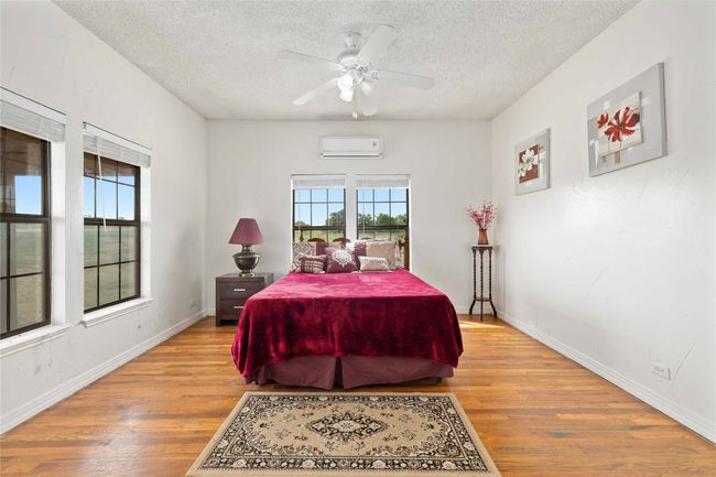 Bedroom featuring a wall mounted AC, a textured ceiling, light wood-style floors, and ceiling fan | Image 17