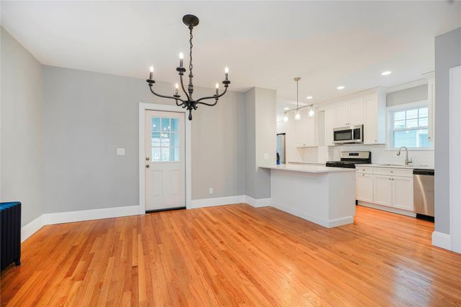 Kitchen featuring a notable chandelier, a peninsula, light wood-style flooring, backsplash, and stainless steel appliances | Image 9