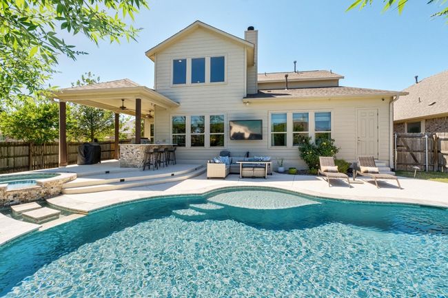 Rear view of property with a fenced in pool, outdoor kitchen, a fenced backyard, a patio area, and an in ground hot tub | Image 34