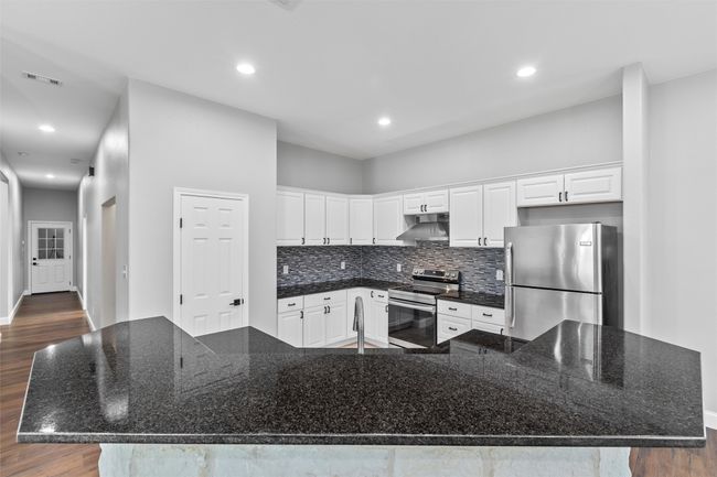 Kitchen with backsplash, a large island, and stainless steel appliances | Image 9