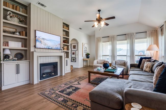 Spacious living area with more custom built ins, electric fireplace, vaulted ceilings, two inch faux blinds, door to outside patio. | Image 7
