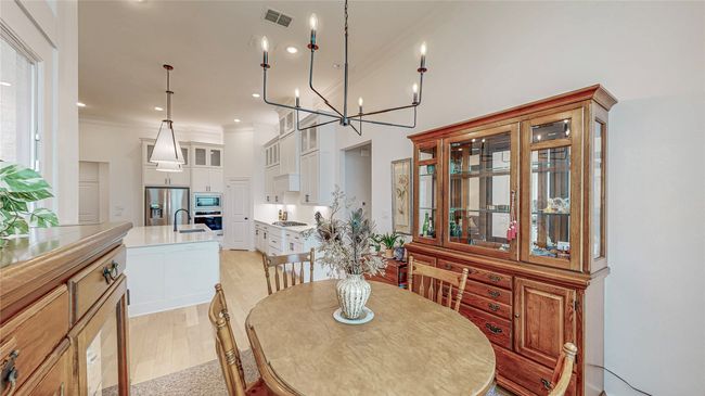 Dining area featuring crown molding, light wood-type flooring, a chandelier, and a towering ceiling | Image 15