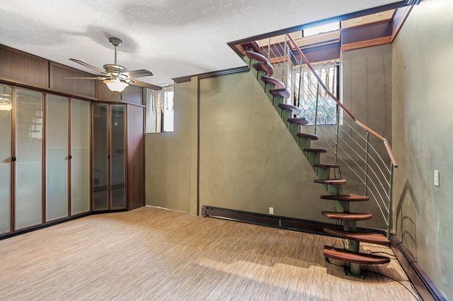 Down the custom metal and wood staircase created exclusively for this space by a German artist. The bedroom is sleek and modern with plenty of storage and a king sized bed. | Image 21