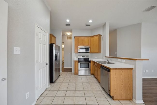 Kitchen featuring appliances with stainless steel finishes, a peninsula, a sink, light countertops, and baseboards | Image 4