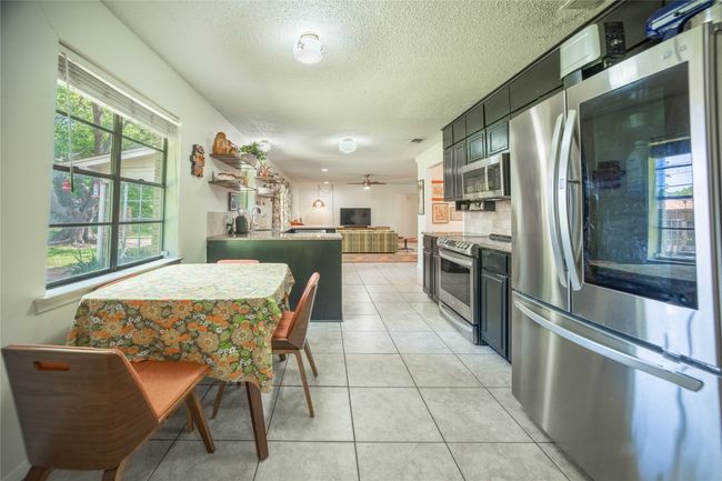 Kitchen featuring light tile patterned floors, stainless steel appliances, a ceiling fan, a textured ceiling, and open floor plan | Image 10
