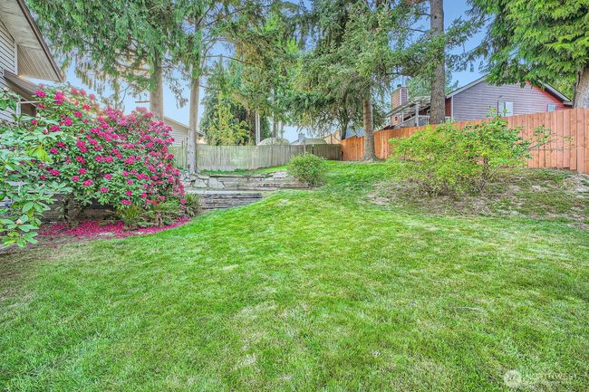 View from green house of upper patio and between the rhododendrons is a small patio outside the lower level sliding glass door. | Image 33
