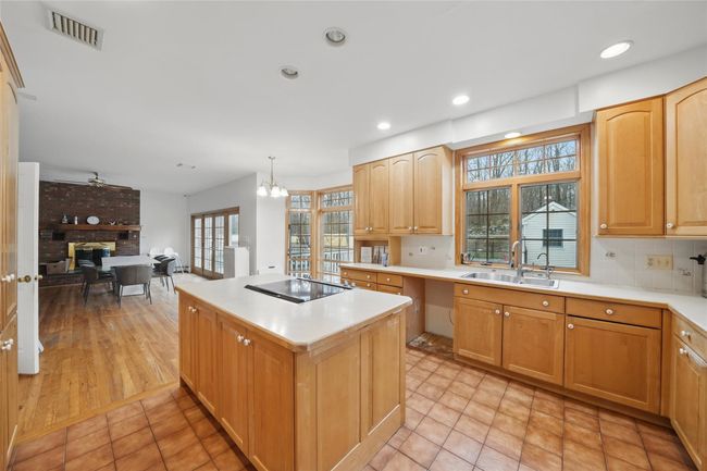 Kitchen with a center island, a sink, stovetop, light countertops, and visible vents | Image 17