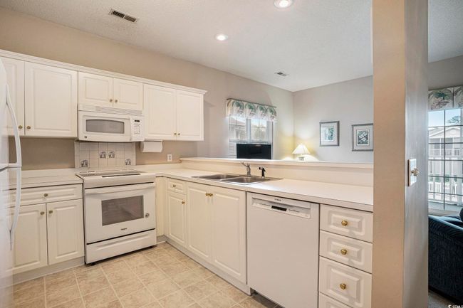 Kitchen featuring white appliances, a sink, healthy amount of natural light, light countertops, and recessed lighting | Image 5