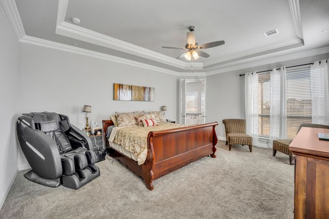 Bedroom featuring a tray ceiling, ceiling fan, crown molding, and light colored carpet | Image 16