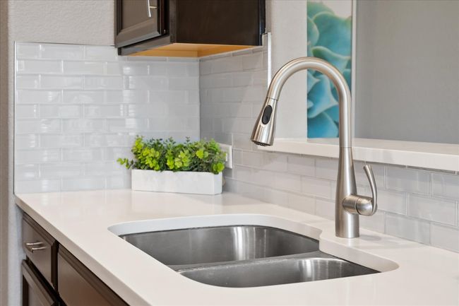 Interior details featuring light countertops, tasteful backsplash, dark brown cabinetry, and a sink | Image 11