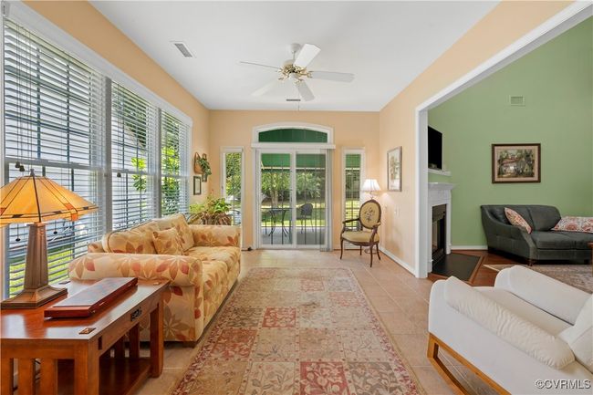 Tiled living room featuring a ceiling fan and a fireplace | Image 13