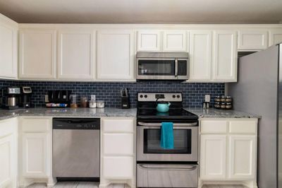 Kitchen with decorative backsplash, fully stocked, granite counters, and stainless steel appliances - 2215 | Image 3