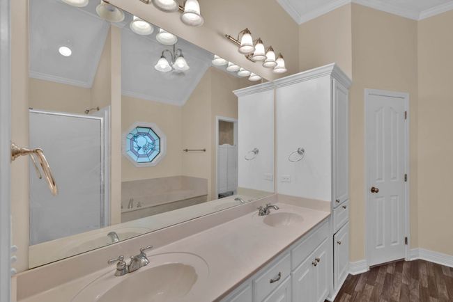 Full bathroom featuring a garden tub, double vanity, a stall shower, crown molding, and wood finished floors | Image 19