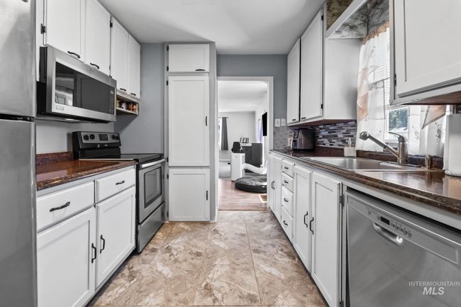 Kitchen with appliances with stainless steel finishes, white cabinets, and tasteful backsplash | Image 17