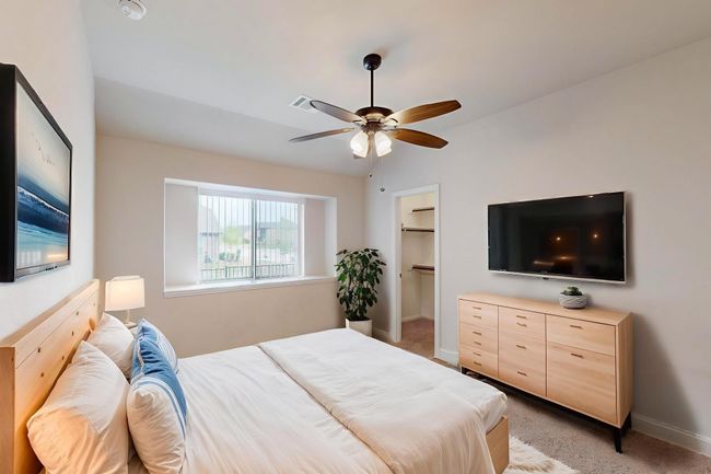 Bedroom featuring light carpet, baseboards, a walk in closet, and ceiling fan | Image 4